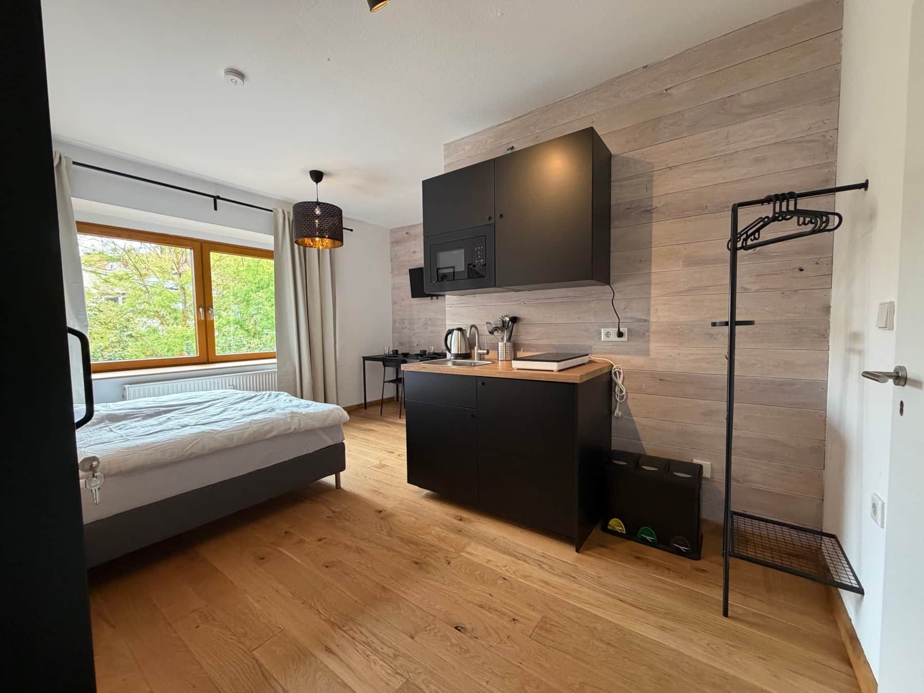 Doppelzimmer mit Bett, Küchenzeile und Fenster